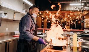 un hombre en una cocina preparando comida en una sartén en Loft Hotel en Bukovel