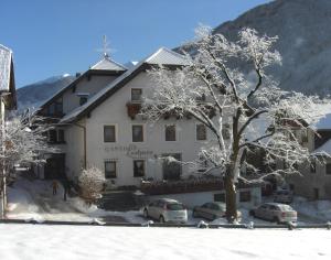 un edificio con coches aparcados frente a él en la nieve en Gasthof Lechner, en Rasun di Sopra
