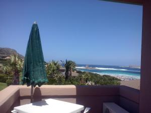 a green umbrella sitting on a balcony with the ocean at Rocca Ruja Vip in Stintino