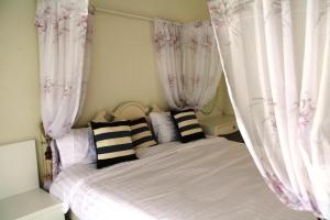 um quarto com uma cama com cortinas cor-de-rosa e brancas em Huen Chan Thip em Chiang Rai