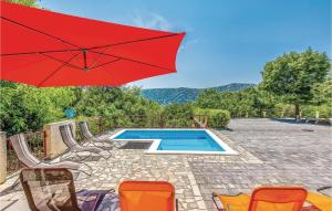 a red umbrella and chairs and a swimming pool at 2 Bedroom Cozy Apartment In Grizane in Kostelj