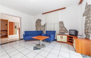 2 Bedroom Cozy Apartment In Grizane في Kostelj: غرفة معيشة مع كراسي زرقاء وطاولة وتلفزيون