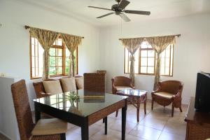 ein Wohnzimmer mit einem Tisch und Stühlen sowie einem Deckenventilator in der Unterkunft Le Surmer Self Catering Chalets in La Digue