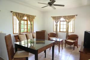a living room with a table and chairs and a ceiling fan at Le Surmer Self Catering Chalets in La Digue
