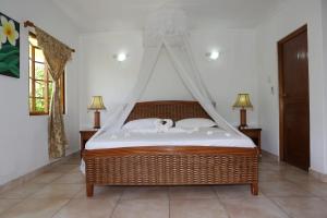 a bedroom with a canopy bed with two dogs on it at Le Surmer Self Catering Chalets in La Digue