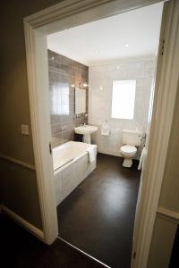 a bathroom with a tub and a toilet and a sink at The Ashbourne Hotel in North Killingholme