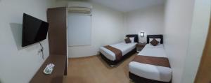 a hotel room with two beds and a flat screen tv at Grand Avira Hotel in Batu Merah