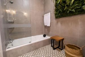 a bathroom with a shower and a tub and a stool at Siji Gempol Vacation Home in Yogyakarta