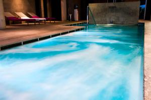 een zwembad met water in een kamer met stoelen bij Hotel Convento Aracena & SPA in Aracena