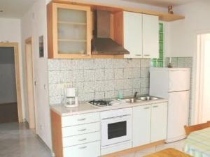 eine Küche mit weißen Schränken und einem weißen Kühlschrank in der Unterkunft Apartment Miranda in Bol