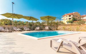 a swimming pool with chairs and umbrellas at Awesome Apartment In Premantura With Wifi And Outdoor Swimming Pool in Premantura