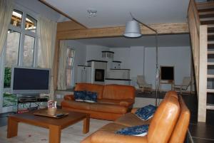 a living room with a couch and a tv at Les Bleuets in Scharrachbergheim Irmstett