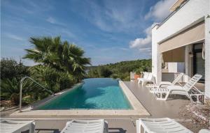 a swimming pool with white chairs next to a house at Stunning Apartment In Pula With 1 Bedrooms, Wifi And Outdoor Swimming Pool in Pula