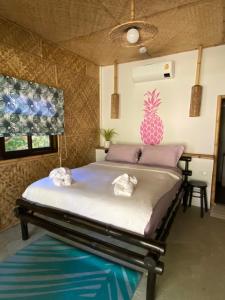 Bett in einem Zimmer mit einer Ananas an der Wand in der Unterkunft Margarita Beach in Khanom