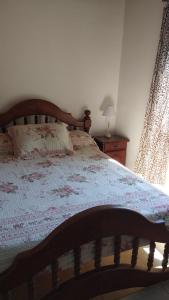 a bedroom with a bed with a wooden headboard and a window at La posada de Icha in El Bolsón