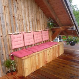 a wooden pergola with pink chairs on a deck at Gîte &quot;La Bergerie&quot;- Chalet indépendant in Kirchberg