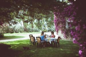 zwei Frauen sitzen an einem Tisch im Gras in der Unterkunft Masseria Perronello Country House in Castellaneta Marina 