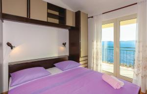 a bedroom with a purple bed and a balcony at Nice Apartment In Omis With 3 Bedrooms And Wifi in Pisak