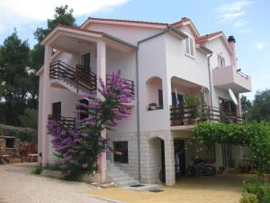 een groot wit huis met paarse bloemen bij Apartments Vanda in Vrboska