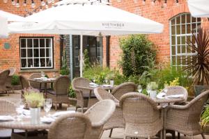 an outdoor patio with tables and chairs and an umbrella at Hotel du Vin Henley in Henley on Thames
