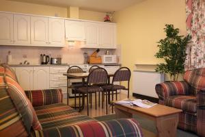 a living room with a kitchen and a table with chairs at Killarney Self-Catering - Haven Suites in Killarney