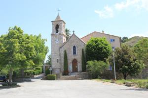 a church with a tower with a clock on it at Ferme de Sejour Rebuffel in La Roque-Esclapon