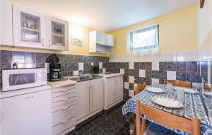 eine Küche mit einem Tisch und einer Mikrowelle in der Unterkunft Amazing Home In Porec With 1 Bedrooms And Wifi in Poreč