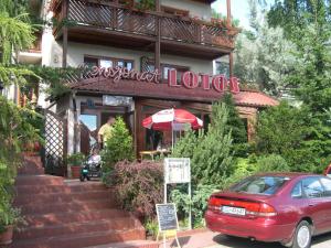 a red car parked in front of a restaurant at Pensjonat Lotos in Krynica Morska