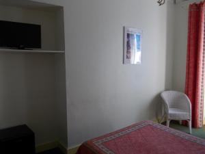a bedroom with a bed and a tv and a chair at Hotel Marcellin in Beaulieu-sur-Mer
