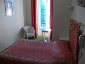 a bedroom with a red bed and a window at Hotel Marcellin in Beaulieu-sur-Mer