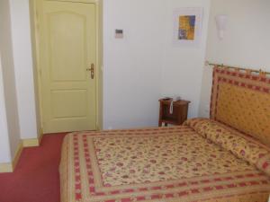 a bedroom with a bed with a yellow door at Hotel Marcellin in Beaulieu-sur-Mer