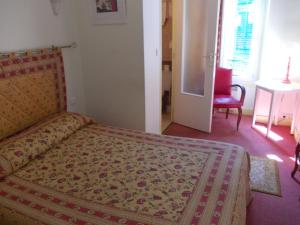 a bedroom with a bed and a table and a chair at Hotel Marcellin in Beaulieu-sur-Mer