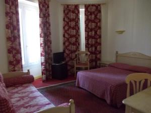 a bedroom with a bed and a couch and a window at Hotel Marcellin in Beaulieu-sur-Mer