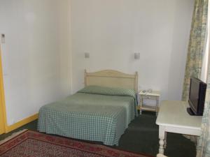 a small bedroom with a bed and a television at Hotel Marcellin in Beaulieu-sur-Mer