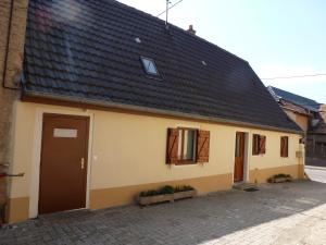 uma casa amarela com um telhado preto e uma porta em Azede em Niederhergheim