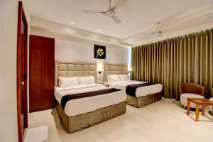 a hotel room with two beds and a chair at Elite Homes in Aurangabad