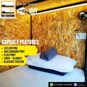 Cartel de una cama en una habitación con pared en The Cocoon Capsule Hotel, en Cameron Highlands