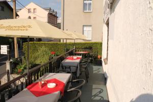 einen Balkon mit Tischen, Stühlen und einem Sonnenschirm in der Unterkunft Záboj restaurant in Karlsbad