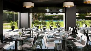 a restaurant with white chairs and tables and windows at Melia Sitges in Sitges
