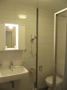 
a bathroom with a sink, toilet and shower at Hotel am Hauptbahnhof in Schwerin
