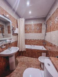a bathroom with a sink, toilet and bathtub at Hotel Snezhny in Sheregesh