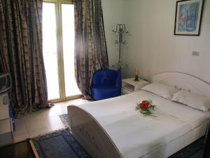 um quarto com uma cama e uma cadeira azul e uma janela em Hotel Hamilton em Hammamet