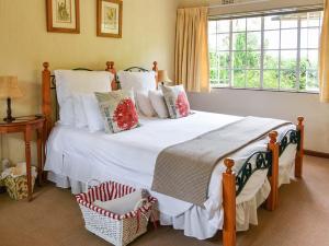 Schlafzimmer mit einem Bett mit weißer Bettwäsche und einem Fenster in der Unterkunft Random Harvest Country Cottages in Muldersdrift