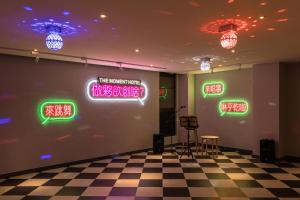 a room with neon signs on a wall with a checkered floor at The Moment Hotel Yilan by Lakeshore in Wujie