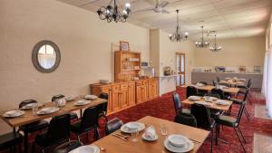 a dining room with tables and chairs and a kitchen at Bishops Lodge Narrandera in Narrandera