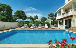 a swimming pool with chairs and umbrellas next to a building at Amazing Apartment In Porec With Wifi in Poreč