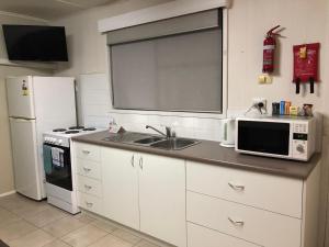 a kitchen with a microwave, refrigerator, sink and dishwasher at Acacia Caravan Park & Holiday Units in Ararat