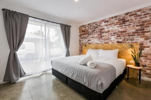 Un dormitorio con una pared de ladrillo y una cama. en Alley Cats, en Margaret River Town