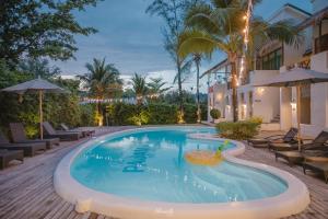 a pool with chairs and umbrellas next to a building at Pajamas Koh Chang in Ko Chang