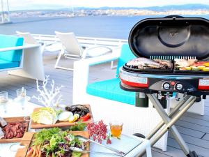 ein Grill auf einer Terrasse mit einem Tisch voller Essen in der Unterkunft CORAL SUITE VILLA awaji in Awaji